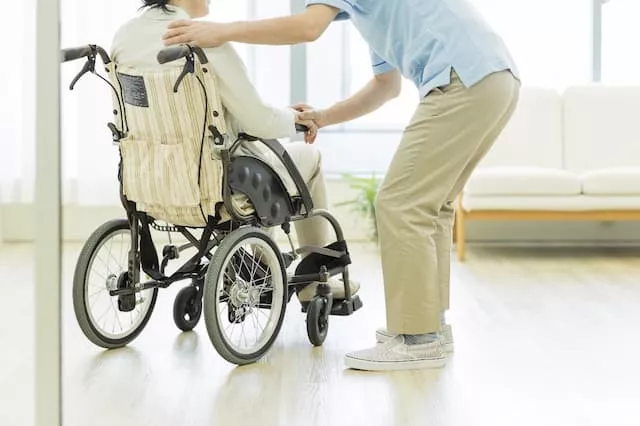車いすに乗った女性に話しかける男性看護助手